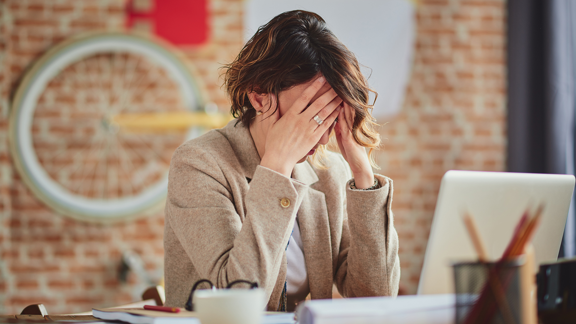 a woman sitting at a desk with her head in her hands.