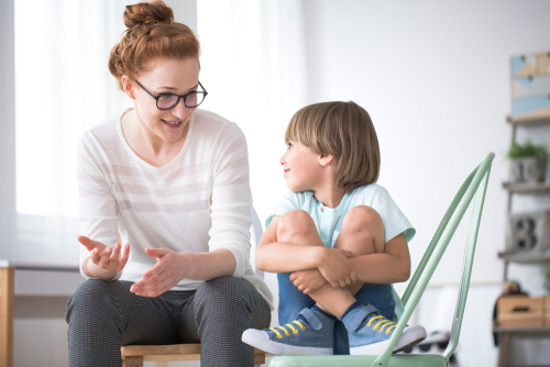 Mother,Talking,To,Her,Smiling,Son,Sitting,On,Green,Chair